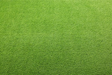 Green artificial grass as background, top view