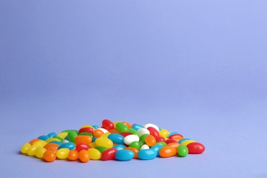 Delicious bright jelly beans on color background. Space for text