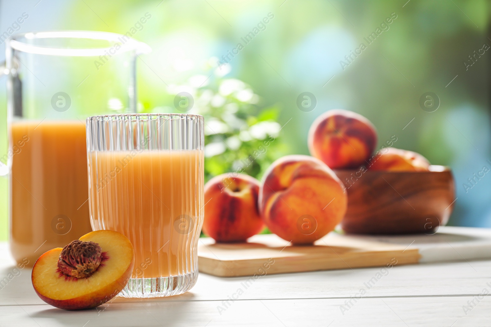 Photo of Glass of peach juice and fresh fruit on white wooden table. Space for text