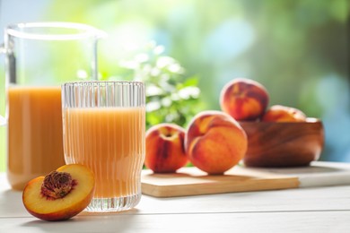 Glass of peach juice and fresh fruit on white wooden table. Space for text