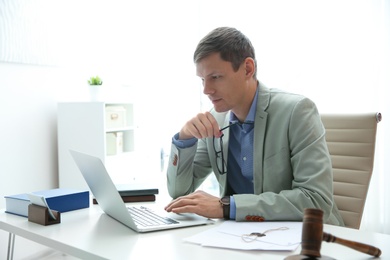 Photo of Notary working with laptop and judge gavel on table in office. Law and justice concept