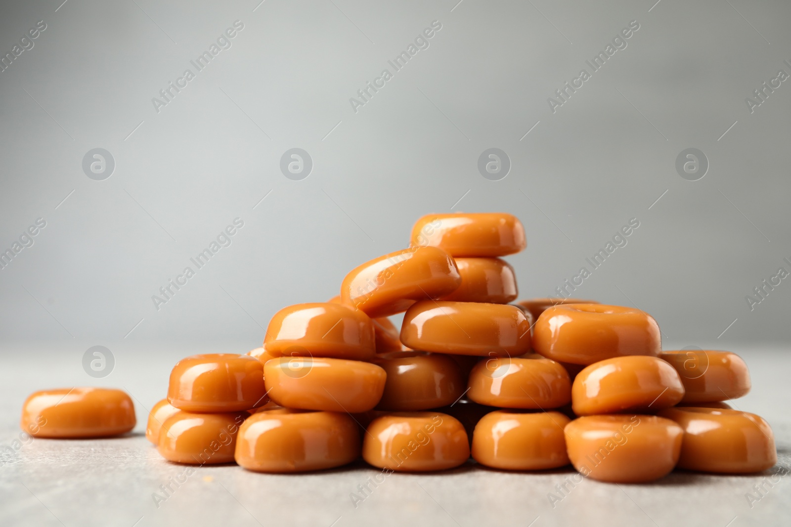 Photo of Tasty hard toffee candies on light grey table, closeup. Space for text