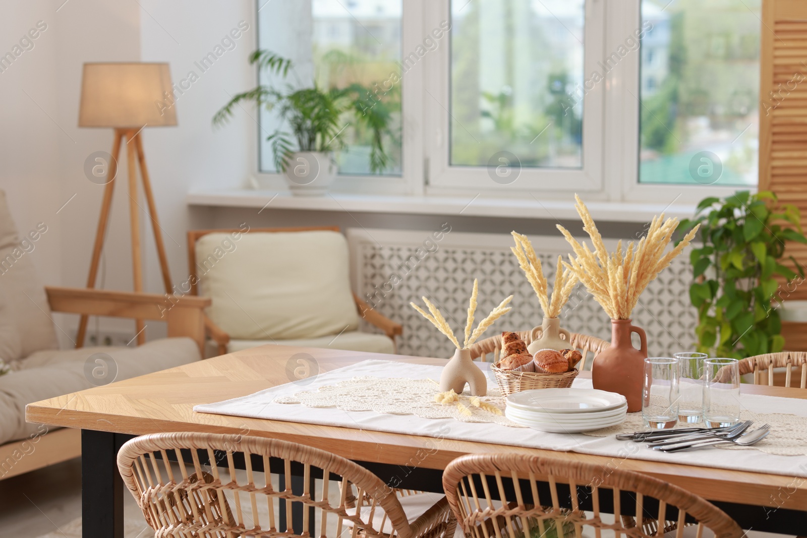 Photo of Clean dishes, dry spikes and fresh pastries on table in stylish dining room