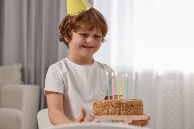 Photo of Cute boy with birthday cake at home