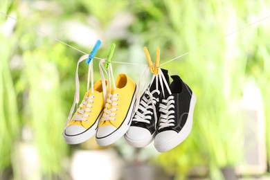 Different stylish sneakers drying on washing line against blurred background