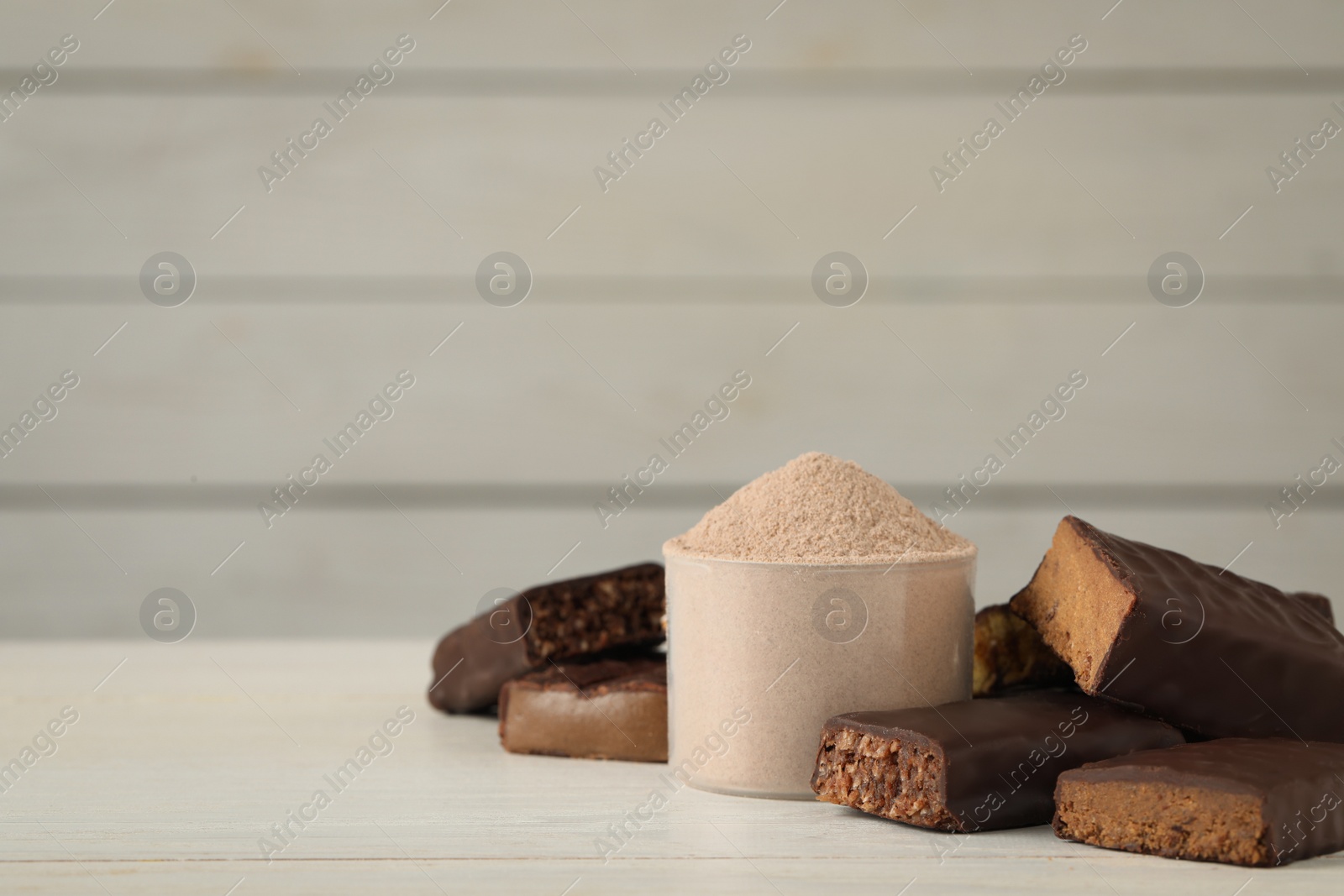 Photo of Different tasty energy bars and protein powder on white table, space for text