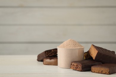 Different tasty energy bars and protein powder on white table, space for text