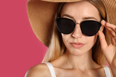 Beautiful woman in stylish sunglasses on pink background, closeup