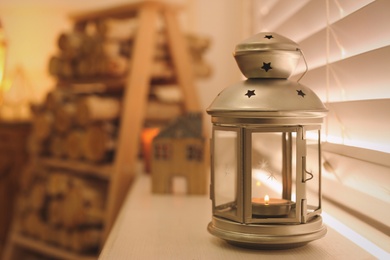 Decorative Christmas lantern with burning candle near window, space for text