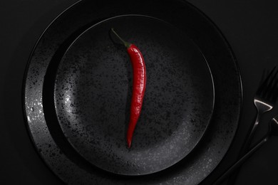 Photo of Stylish table setting. Plates, cutlery and red chilli pepper on black background, top view
