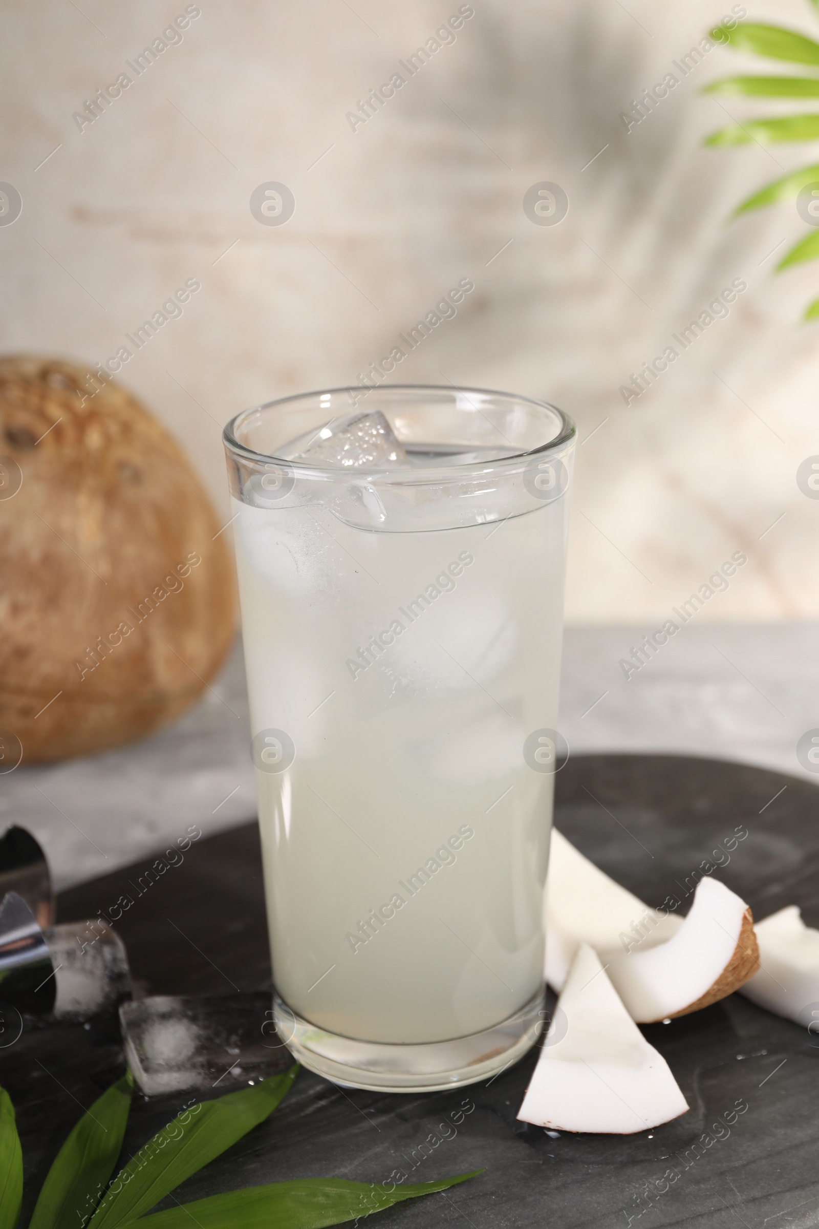 Photo of Glass of coconut water, ice cubes and nuts on table