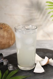 Photo of Glass of coconut water, ice cubes and nuts on table