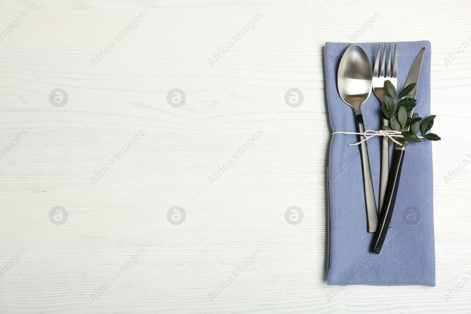 Photo of Cutlery and napkin on light wooden background, top view. Table setting