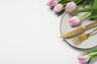 Photo of Stylish table setting with cutlery and tulips on white background, flat lay. Space for text