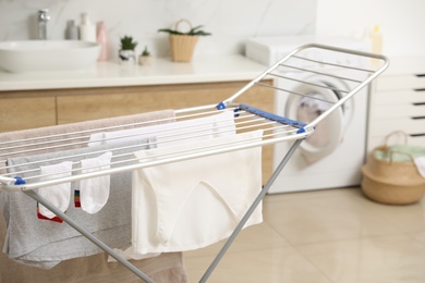 Clean laundry hanging on drying rack in bathroom, closeup