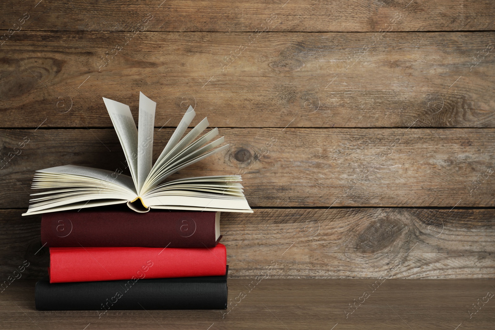 Photo of Stack of hardcover books on wooden table, space for text