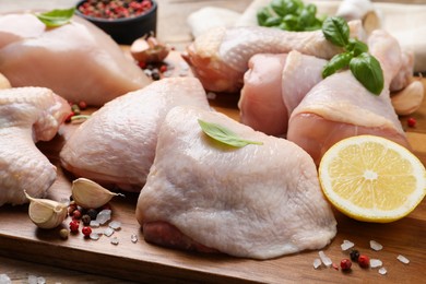 Fresh raw chicken meat and other products on wooden board, closeup