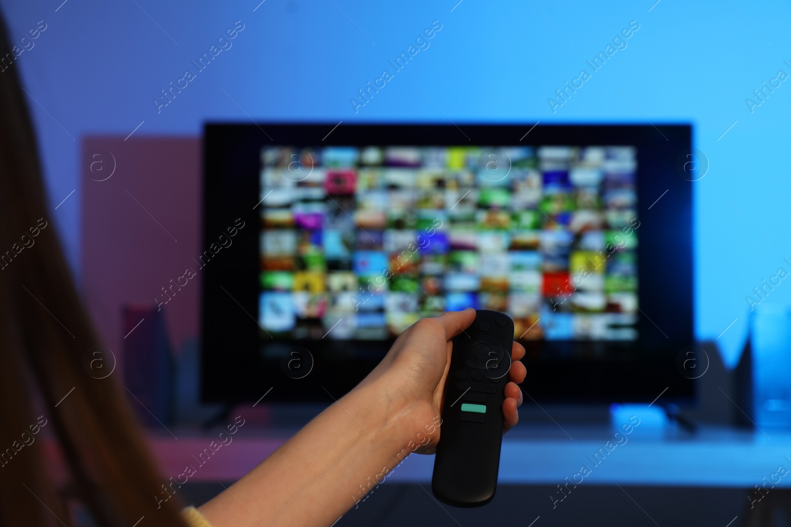 Photo of Woman switching channels on TV set with remote control at home, closeup