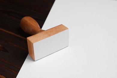 One stamp tool and sheet of paper on wooden table, closeup. Space for text