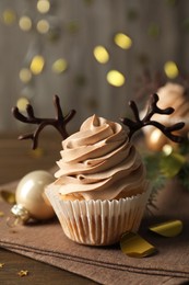 Photo of Tasty Christmas cupcake with chocolate reindeer antlers on wooden table