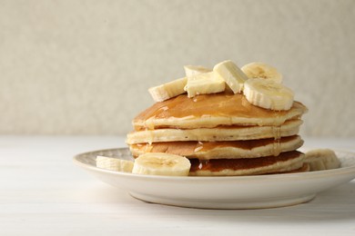 Photo of Delicious pancakes with bananas, honey and butter on white wooden table, closeup. Space for text