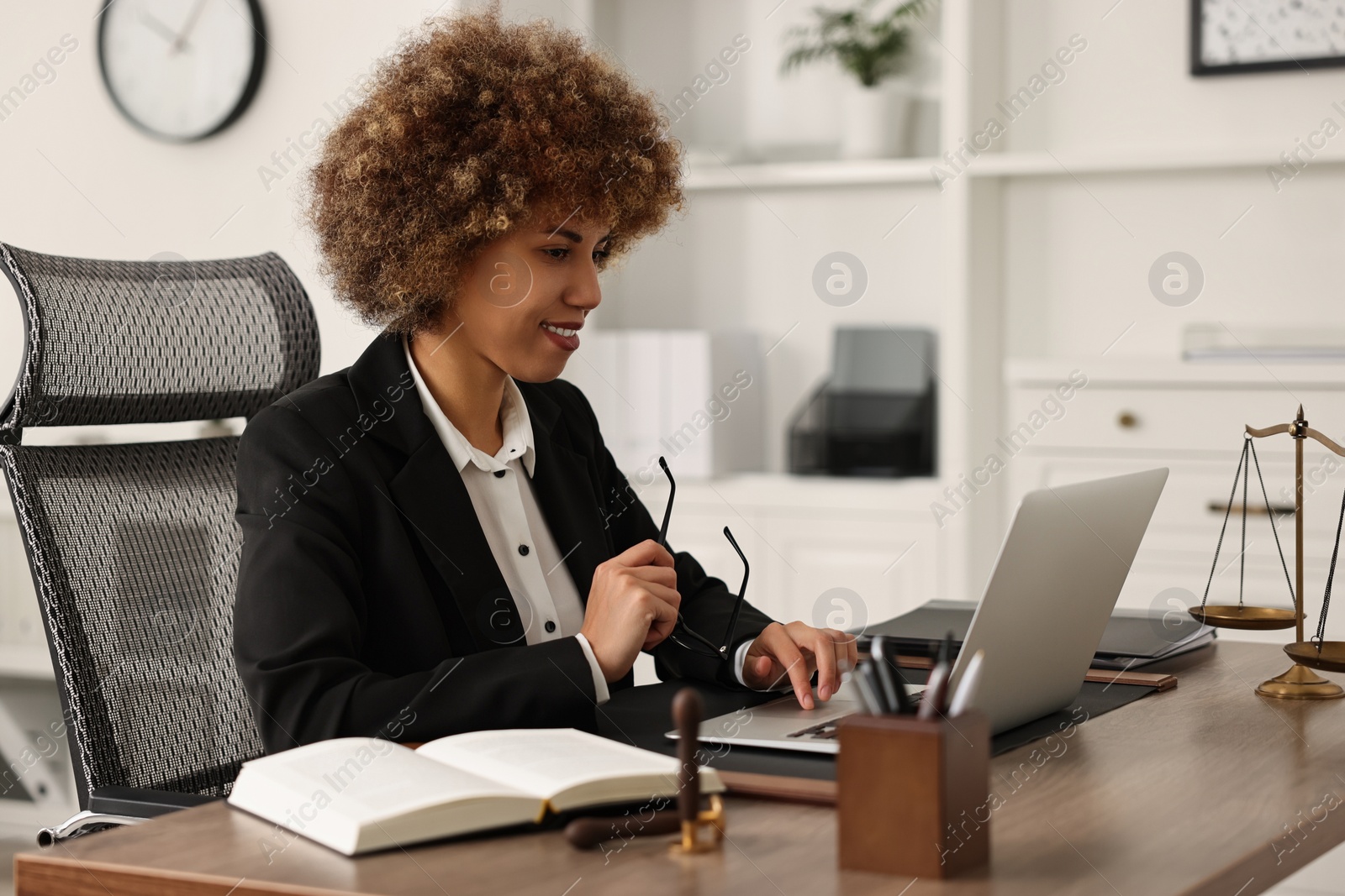 Photo of Notary with glasses using laptop at workplace in office