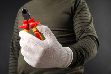 Man with diagonal pliers on dark background, closeup. Space for text