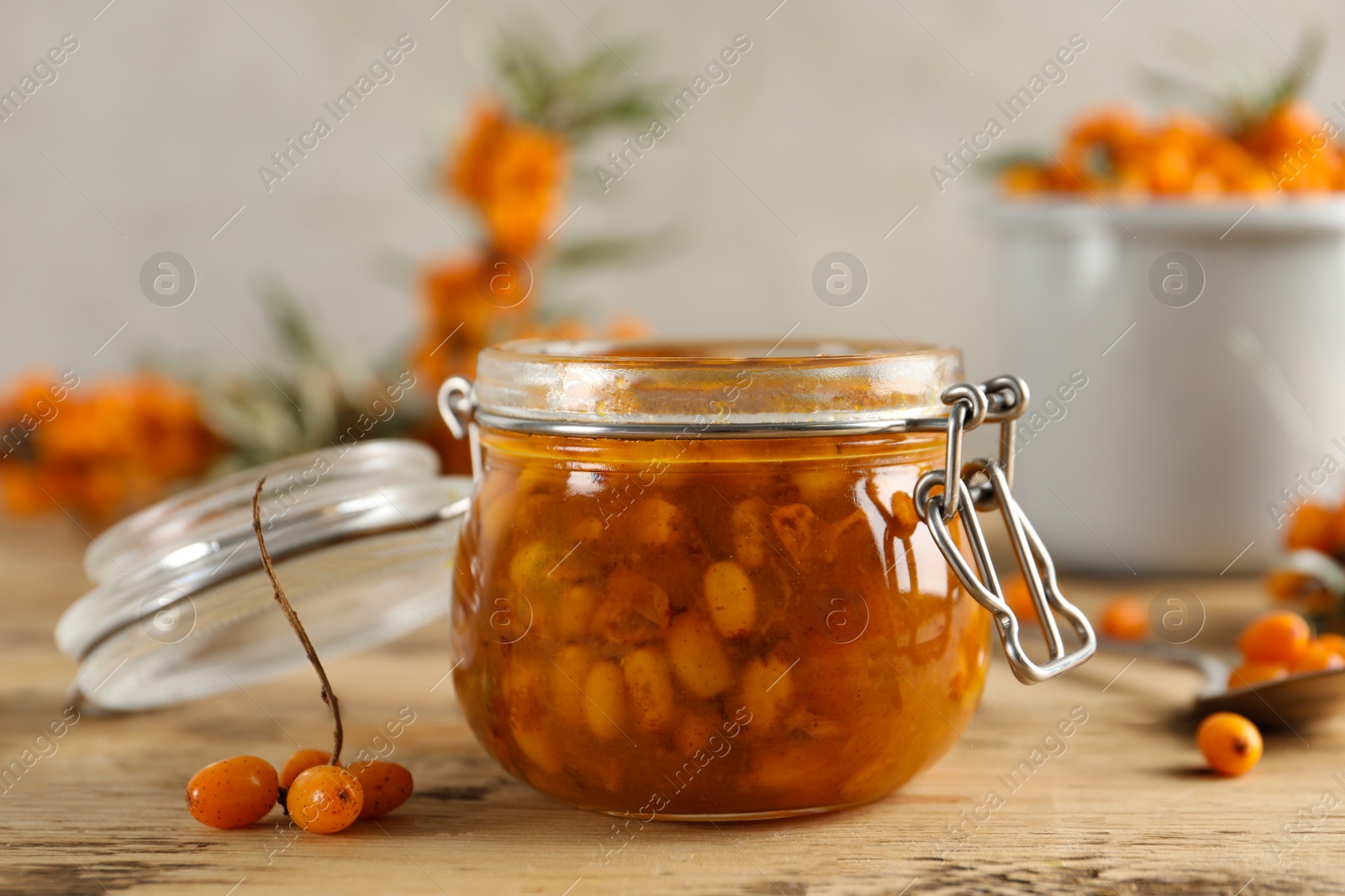 Photo of Delicious sea buckthorn jam and fresh berries on wooden table