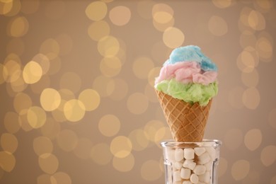 Photo of Sweet cotton candy in waffle cone against blurred lights. Space for text