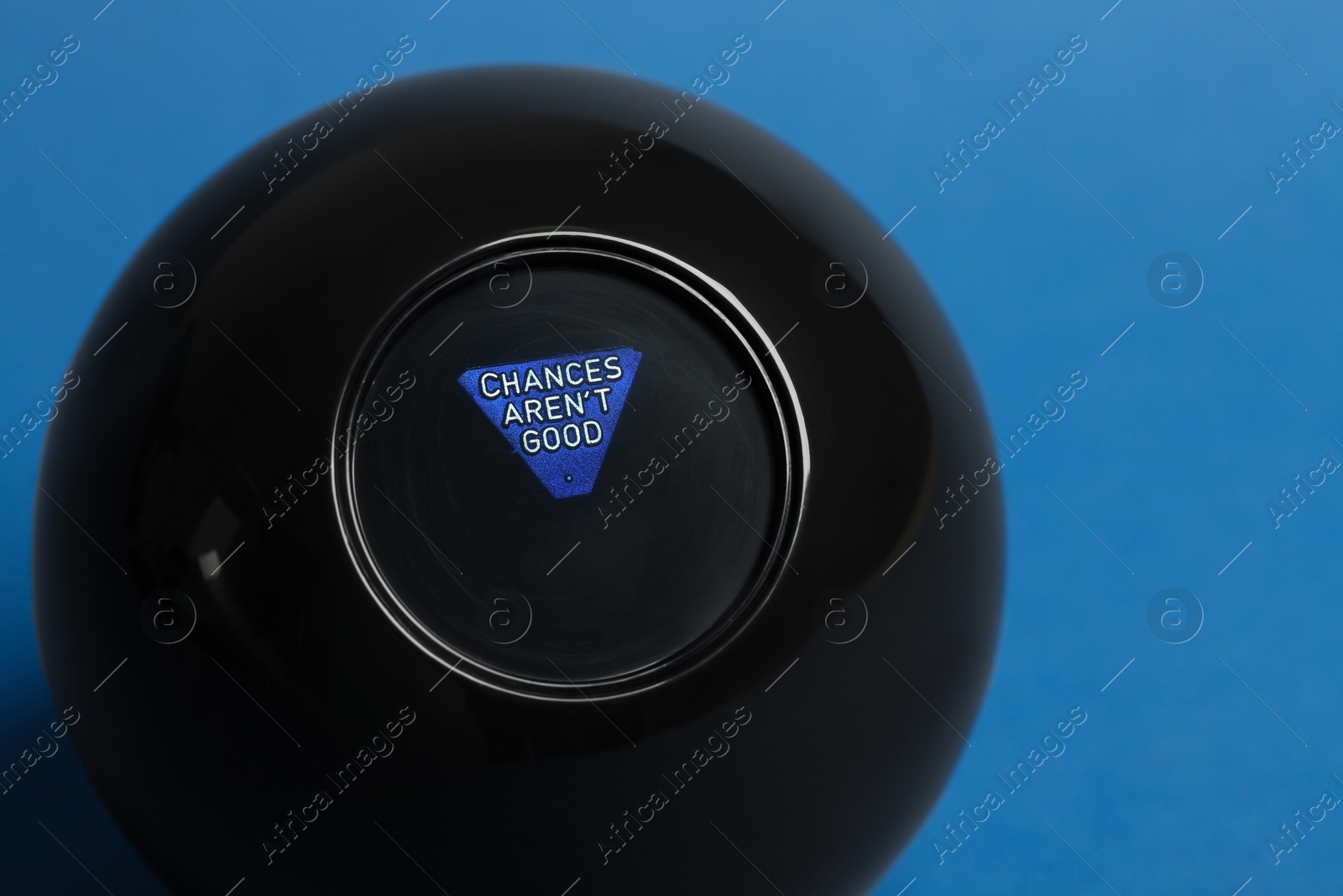 Photo of Magic eight ball on blue background, closeup
