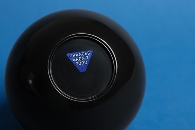 Photo of Magic eight ball on blue background, closeup