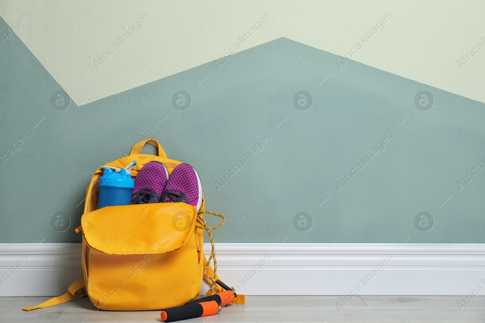 Photo of Sports bag with gym equipment on floor indoors