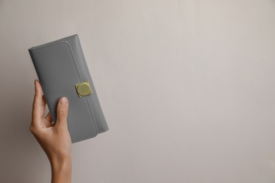 Photo of Woman holding grey leather purse on light background, closeup. Space for text