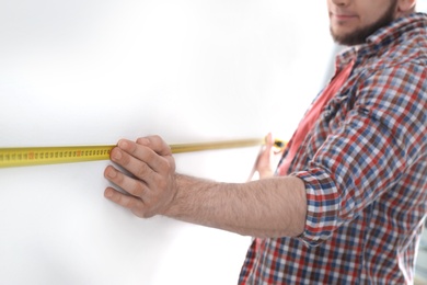 Photo of Man measuring white wall, closeup. Construction tool