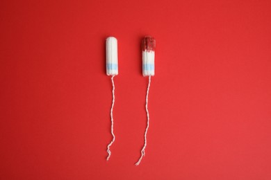 Photo of New and used tampons on red background, flat lay