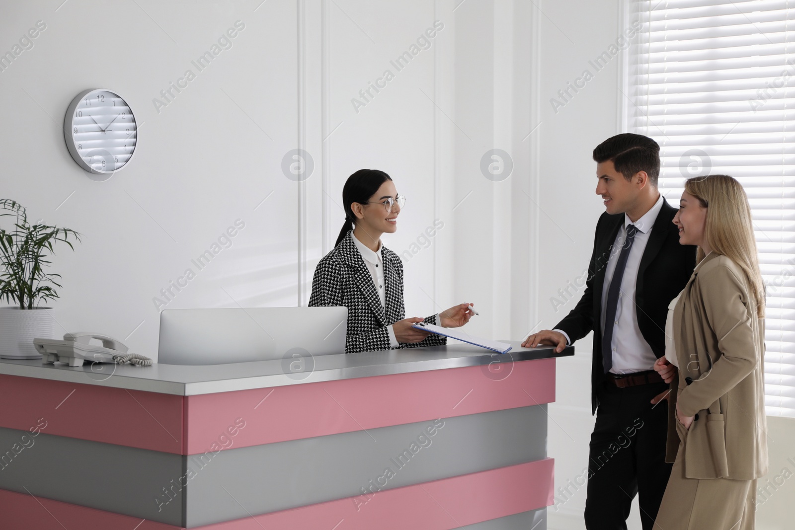 Photo of Receptionist working with clients at countertop in office