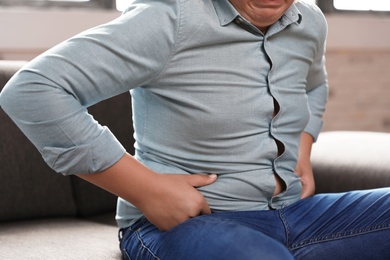 Overweight boy sitting on sofa at home, closeup view