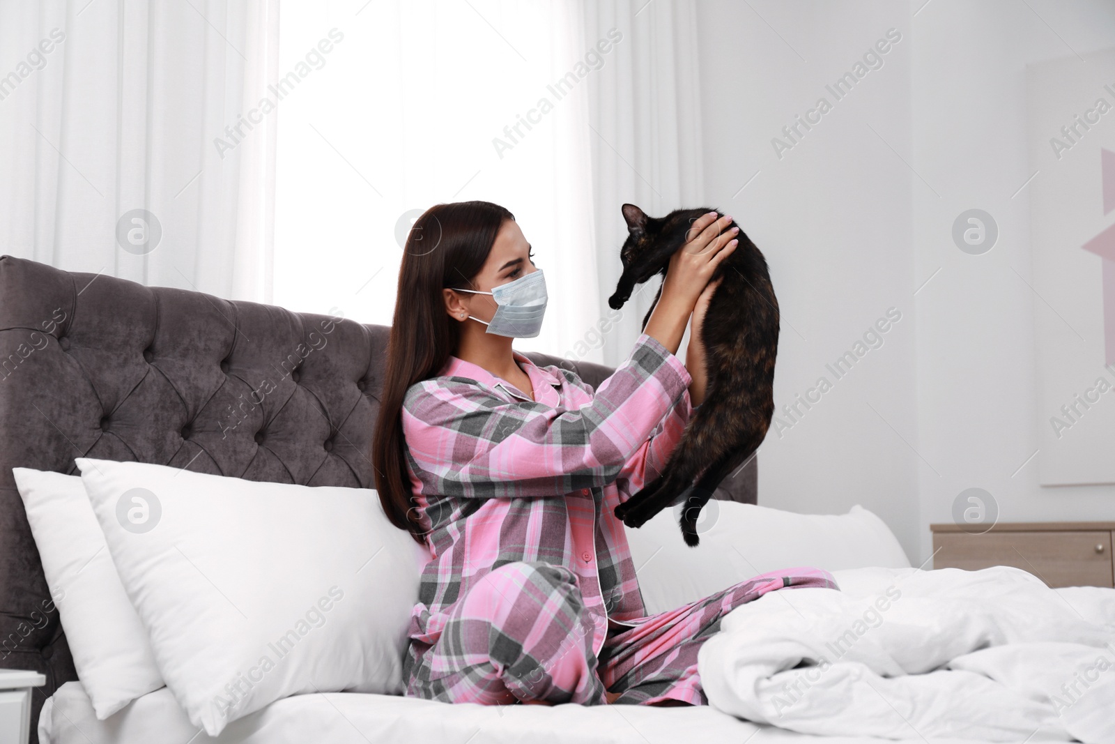 Photo of Young woman with cat suffering from allergy in bedroom