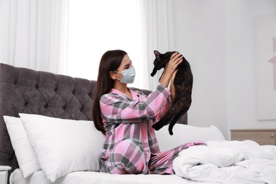 Young woman with cat suffering from allergy in bedroom