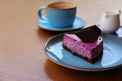 Photo of Plate with slice of berry cheesecake on wooden table