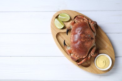 Photo of Delicious boiled crab served with lime and sauce on white wooden table, top view. Space for text