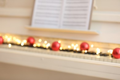Photo of Blurred view of white piano with festive decor, closeup. Christmas music