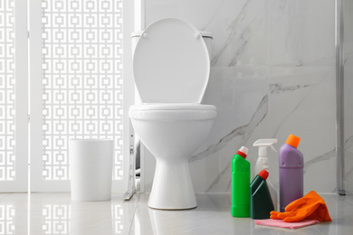 Photo of Toilet bowl and cleaning supplies in modern bathroom