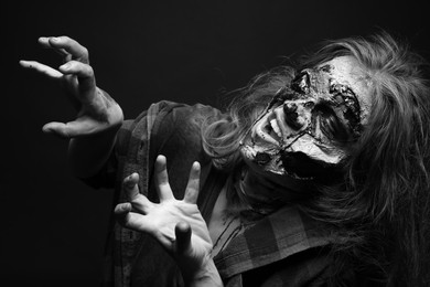 Photo of Scary zombie on dark background, black and white effect. Halloween monster