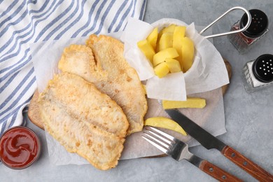 Photo of Delicious fish and chips served on gray table, flat lay