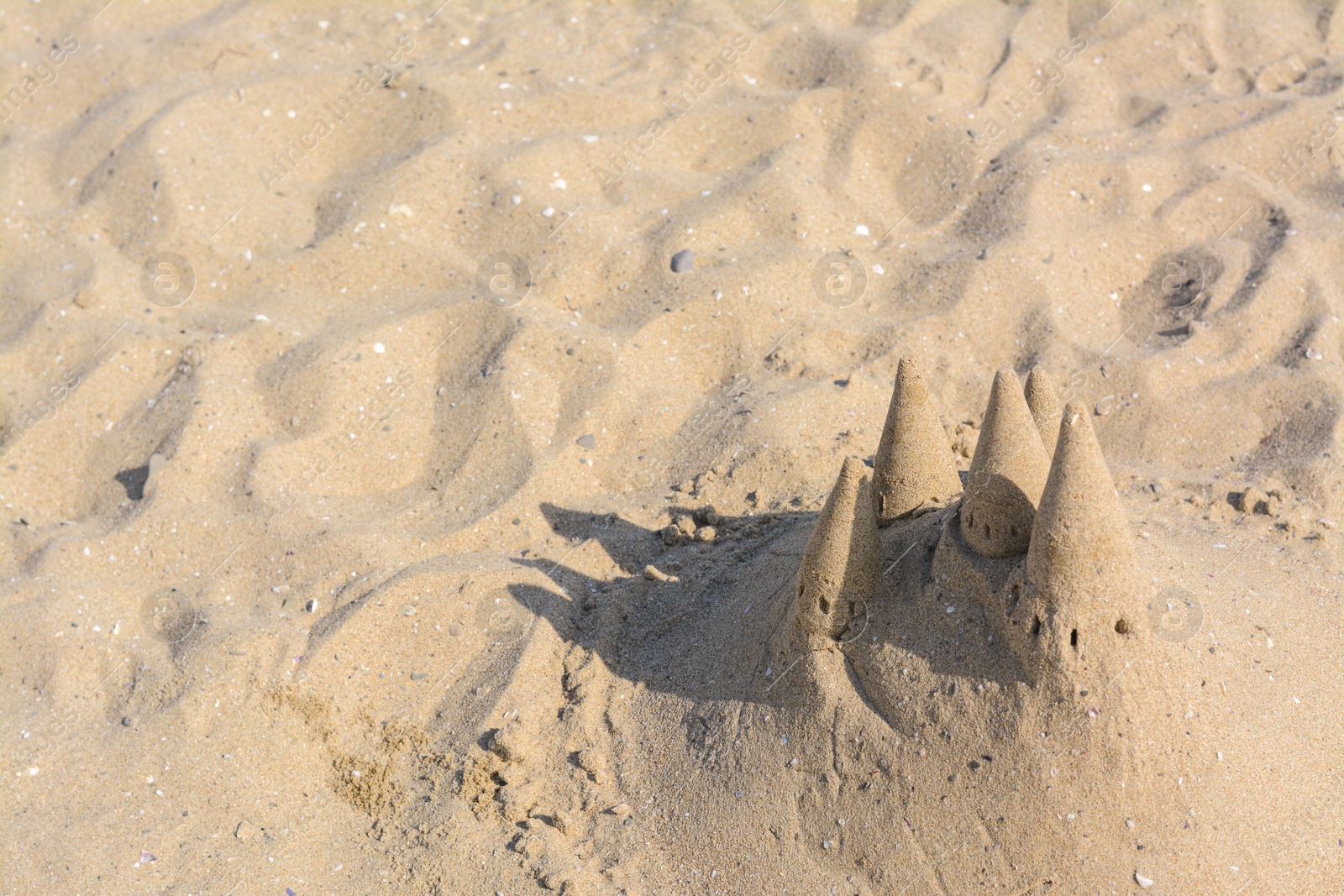 Photo of Beach with sand castle on sunny day, above view. Space for text