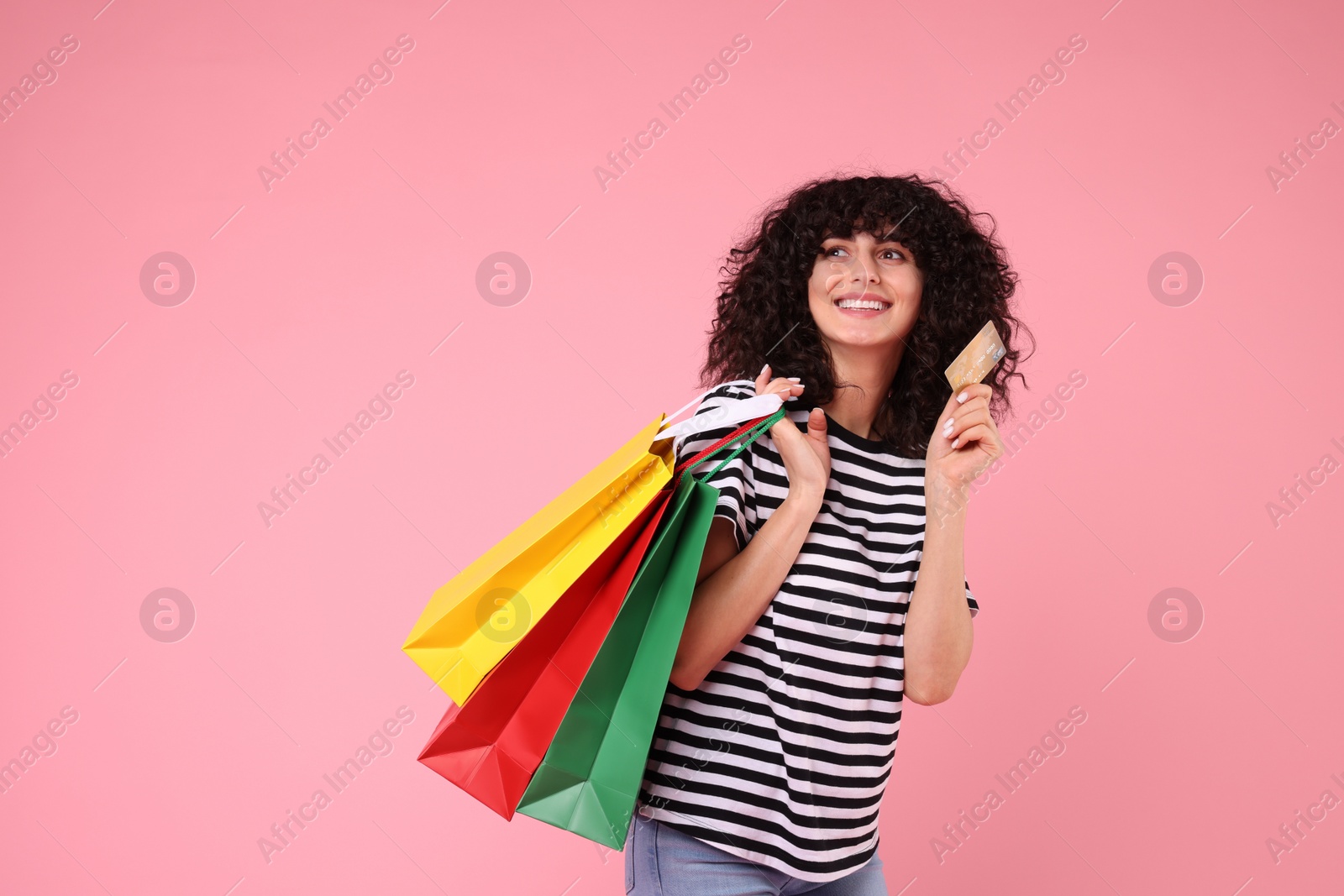 Photo of Happy young woman with shopping bags on pink background