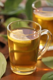 Cups of tasty iced tea with lemon on wooden table, closeup