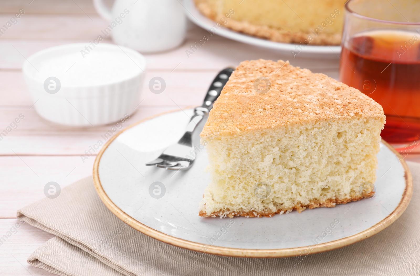 Photo of Piece of tasty sponge cake on white table, closeup