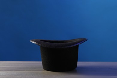 Photo of Magician's hat on wooden table against blue background